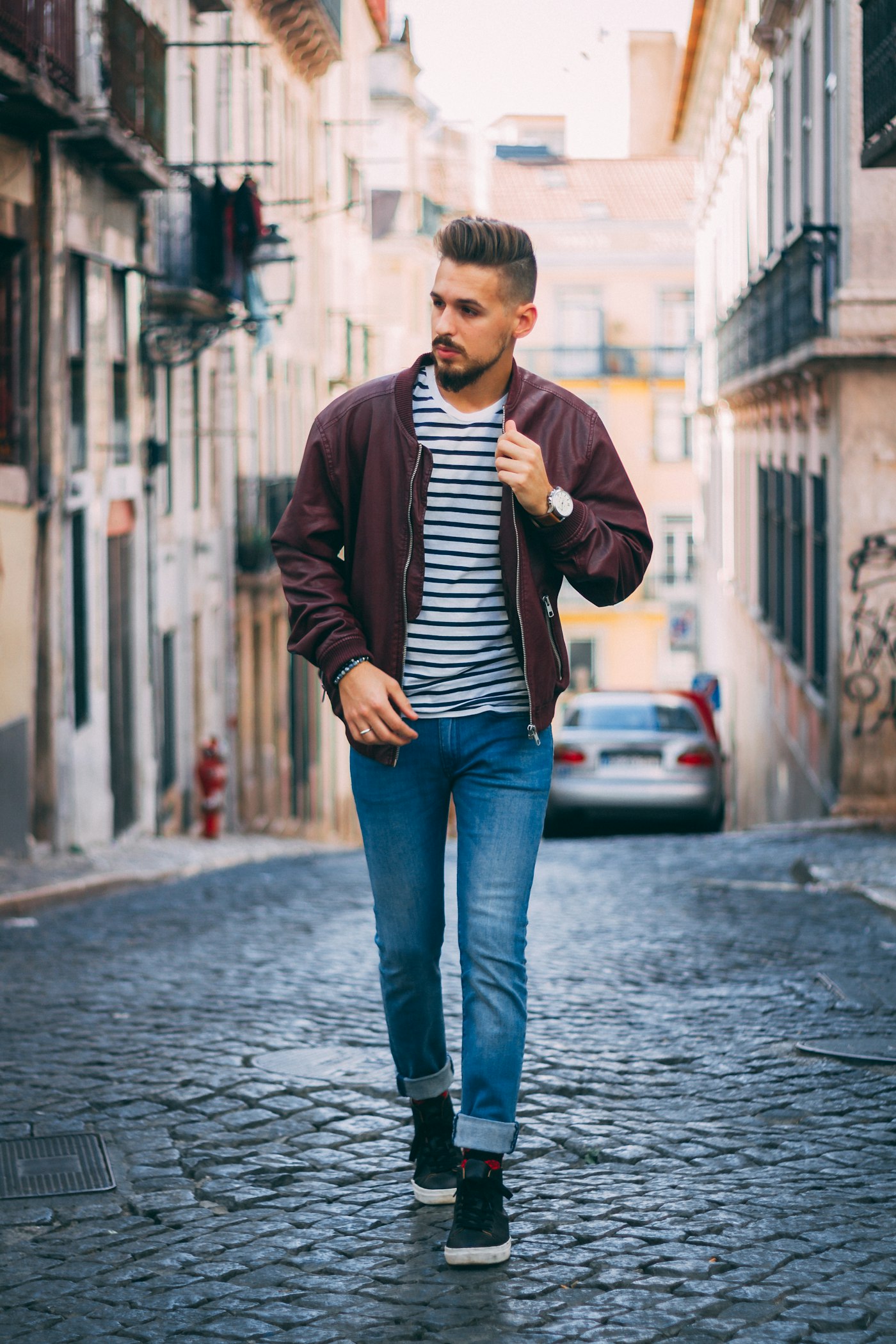 Man walking a cobblestone street in a bomber jacket